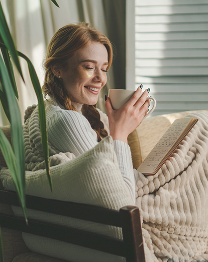 Junge Frau lächelnd mit Tasse in der Hand